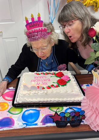 Sarah B of Kenmore senior living blows the candles out on her birthday cake