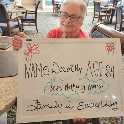 Dorothy of  Pacifica Senior Living Vista holds a sign with motherly advice