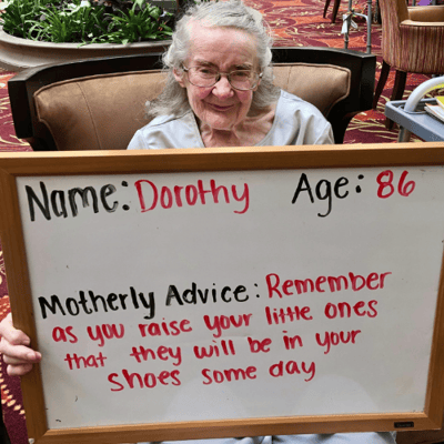 dorothy of Pacifica Senior Living Westwood holds a sign with motherly advice