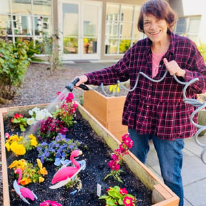a resident of pacifica senior living mission villa waters a garden full of flowers