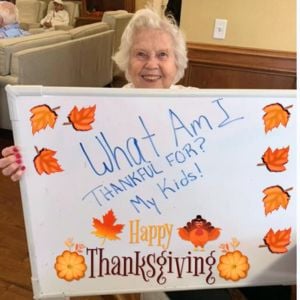 female resident pacifica senior living paradise valley holds a sign to say she is thankful for her kids