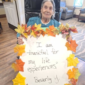 senior woman holds a sign saying she is thankful for her life experiences