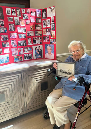 Sarah B of Kenmore Senior Living poses with old photos from her past