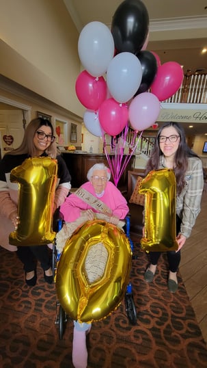 pauline a resident of pacifica senior living chino hills celebrates with staff and balloons that say 101