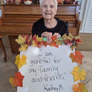senior female resident shares thanksgiving sign saying she is thankful for family and friends