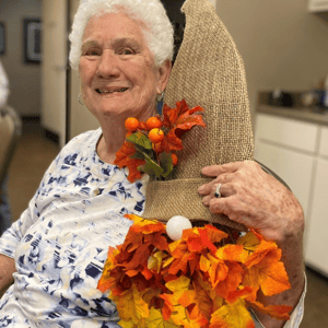 a resident of pacifica senior living holds up a crafted gnome with burlap hat and leaf beard