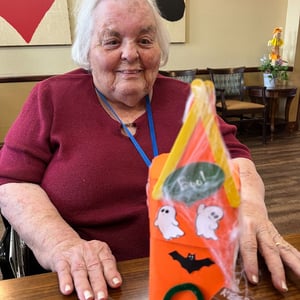 pacifica senior living resident shows off her paper haunted mansion craft