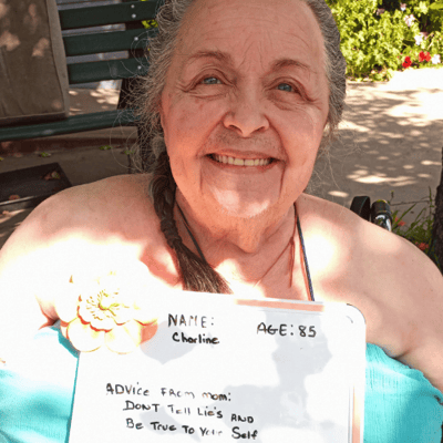 pacifica senior living resident charline holds up her mothers day advice sign