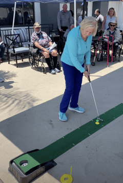 a resident at pacifica senior living rancho penasqitos takes a swing on a golf putting line