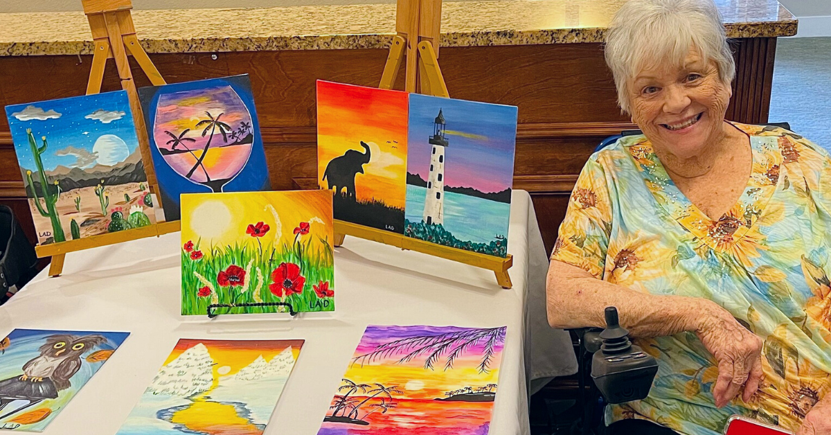 a resident of Pacifica Senior Living shows off some paintings