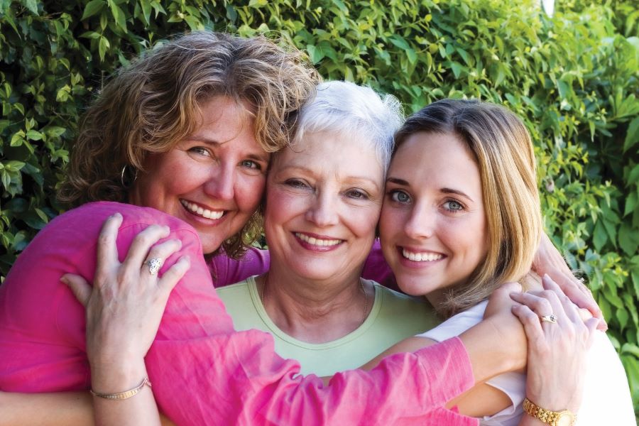 Three generations of women hug each other and smile